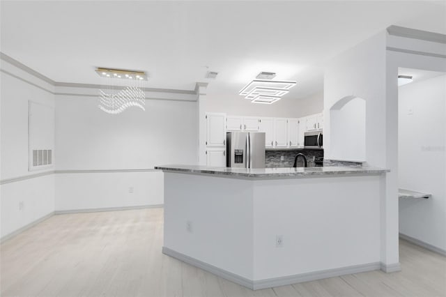 3280 Soho St Unit 306, Orlando, FL 32835 - kitchen featuring appliances with stainless steel finishes, light stone countertops, white cabinetry, light wood-type flooring, and a peninsula