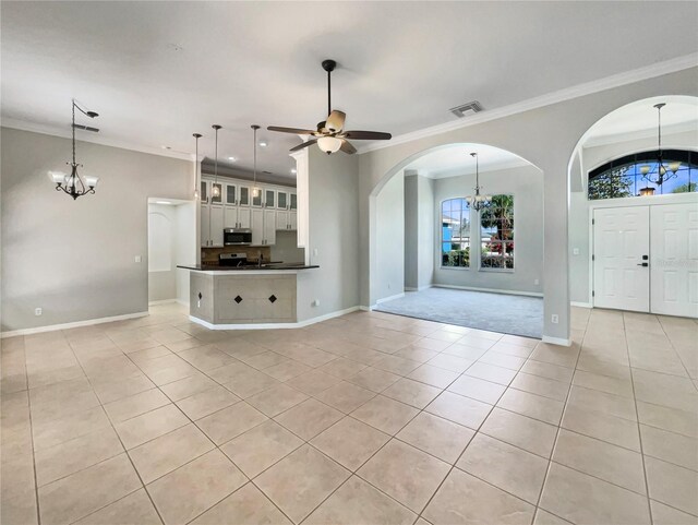 13108 Long Pine Trl, Clermont, FL 34711 - unfurnished living room with a chandelier, light tile patterned floors, ornamental molding, arched walkways, and a ceiling fan