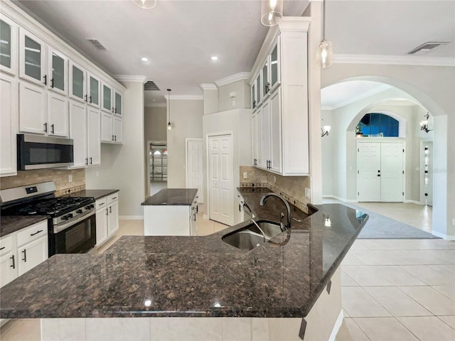 13108 Long Pine Trl, Clermont, FL 34711 - kitchen with appliances with stainless steel finishes, a kitchen island, arched walkways, ornamental molding, and decorative backsplash
