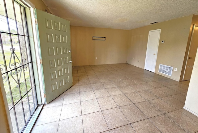empty room with a textured ceiling and light tile patterned flooring