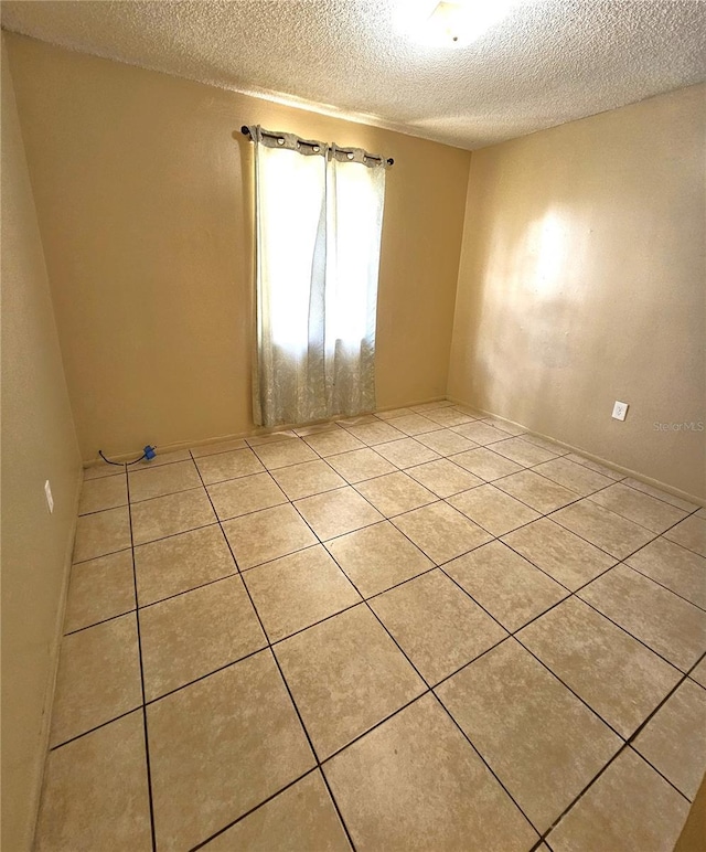 tiled spare room featuring a textured ceiling