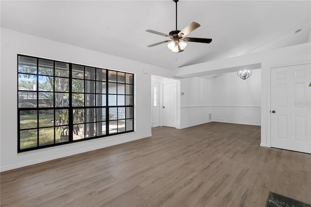 762 Lake Como Dr, Lake Mary, FL 32746 - unfurnished living room with a ceiling fan, wood finished floors, a chandelier, lofted ceiling, and a wainscoted wall