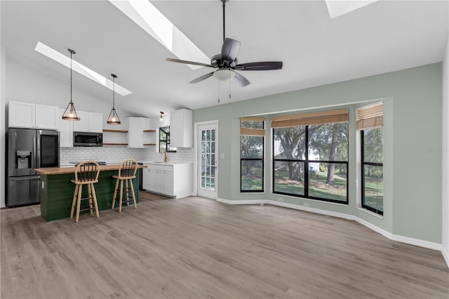 762 Lake Como Dr, Lake Mary, FL 32746 - kitchen featuring stainless steel appliances, a skylight, open shelves, white cabinetry, and lofted ceiling