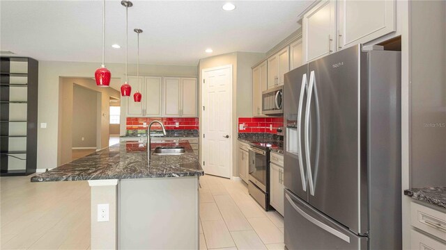 922 Suffolk Pl, Davenport, FL 33896 - kitchen featuring stainless steel appliances, decorative backsplash, recessed lighting, a kitchen island with sink, and dark stone countertops