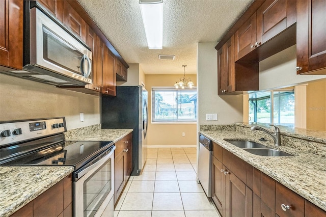 2002 Culpepper Dr, Brandon, FL 33511 - kitchen with stainless steel appliances, a textured ceiling, light tile patterned floors, decorative light fixtures, and a chandelier