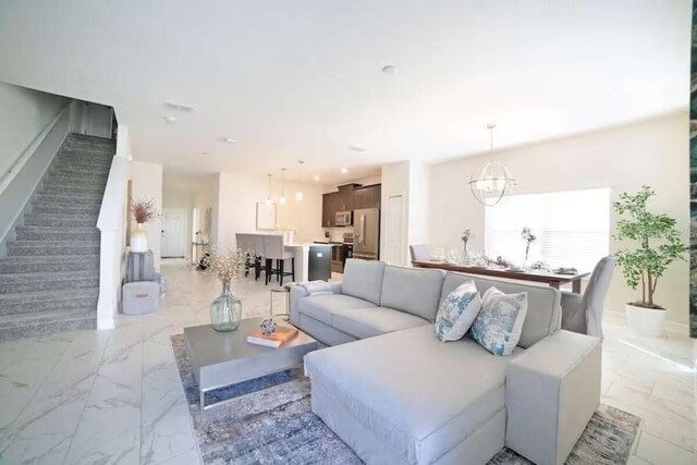 4973 Windermere Ave, Kissimmee, FL 34746 - living area featuring light marble finish flooring, stairway, and a chandelier