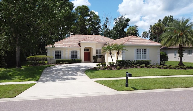 1679 Shadowmoss Cir, Lake Mary, FL 32746 - mediterranean / spanish-style home with driveway, a front yard, a tile roof, and stucco siding