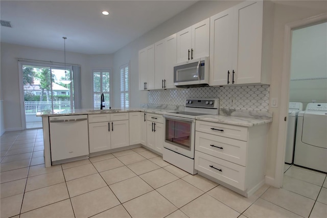 1679 Shadowmoss Cir, Lake Mary, FL 32746 - kitchen featuring white appliances, washer and dryer, white cabinets, a peninsula, and recessed lighting