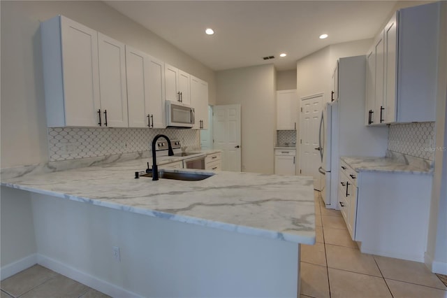 1679 Shadowmoss Cir, Lake Mary, FL 32746 - kitchen with white appliances, a peninsula, tasteful backsplash, light stone countertops, and recessed lighting