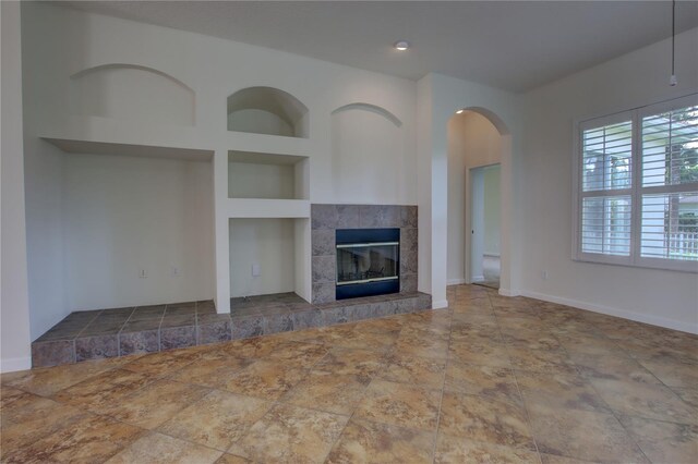 1679 Shadowmoss Cir, Lake Mary, FL 32746 - unfurnished living room with built in features, arched walkways, a tile fireplace, and stone finish flooring