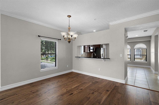 4244 Messina Dr, Lake Mary, FL 32746 - unfurnished dining area with a chandelier, healthy amount of natural light, hardwood / wood-style floors, crown molding, and a textured ceiling