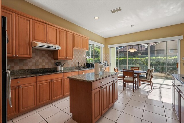 9128 Phillips Grove Ter, Orlando, FL 32836 - kitchen featuring under cabinet range hood, backsplash, a kitchen island, dark stone counters, and pendant lighting