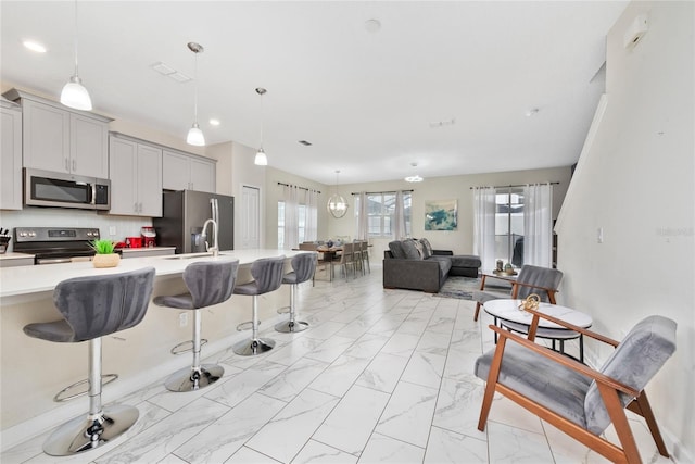 4974 Windermere Ave, Kissimmee, FL 34746 - kitchen with appliances with stainless steel finishes, light marble finish flooring, light countertops, a kitchen bar, and recessed lighting