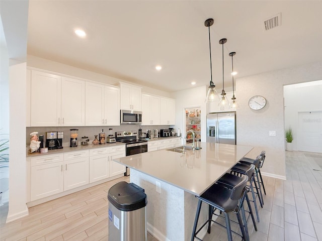13993 Title Way, Winter Garden, FL 34787 - kitchen with appliances with stainless steel finishes, tasteful backsplash, an island with sink, a kitchen breakfast bar, and white cabinets