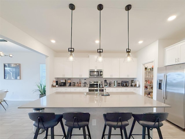 13993 Title Way, Winter Garden, FL 34787 - kitchen featuring appliances with stainless steel finishes, a kitchen bar, hanging light fixtures, white cabinetry, and recessed lighting
