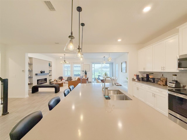 13993 Title Way, Winter Garden, FL 34787 - kitchen with appliances with stainless steel finishes, open floor plan, recessed lighting, white cabinetry, and pendant lighting