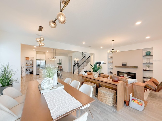 13993 Title Way, Winter Garden, FL 34787 - dining space with stairs, a chandelier, light wood-type flooring, recessed lighting, and a glass covered fireplace