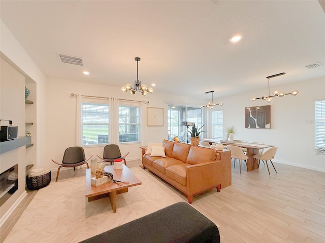 13993 Title Way, Winter Garden, FL 34787 - living room featuring a chandelier, light wood-type flooring, recessed lighting, built in features, and a glass covered fireplace