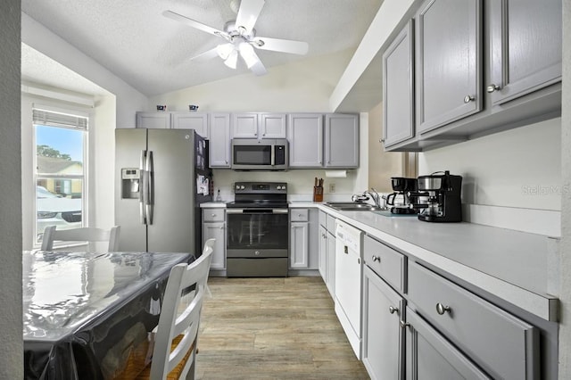 3280 Villa Way Cir, Saint Cloud, FL 34769 - kitchen featuring stainless steel appliances, light wood-style floors, vaulted ceiling, a ceiling fan, and gray cabinetry