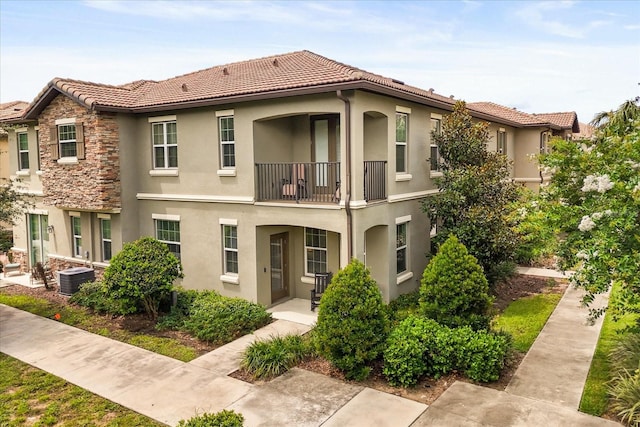 1351 Shinnecock Hills Dr, Davenport, FL 33896 - back of house with a balcony, stucco siding, a tile roof, and stone siding