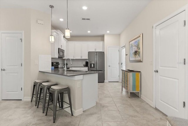 1351 Shinnecock Hills Dr, Davenport, FL 33896 - kitchen with stainless steel refrigerator with ice dispenser, a peninsula, white cabinetry, a breakfast bar, and dark countertops