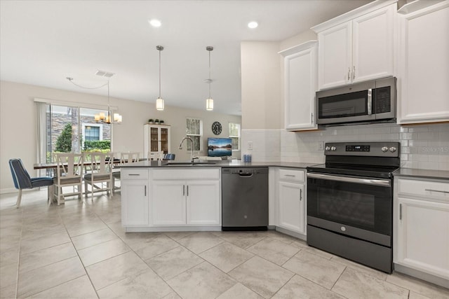 1351 Shinnecock Hills Dr, Davenport, FL 33896 - kitchen featuring stainless steel appliances, dark countertops, a peninsula, backsplash, and recessed lighting