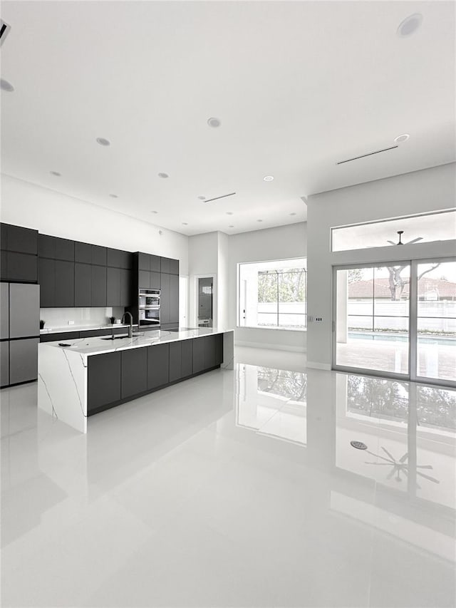 9 Edison Ln, Palm Coast, FL 32164 - kitchen with modern cabinets, light tile patterned floors, light countertops, a large island with sink, and appliances with stainless steel finishes