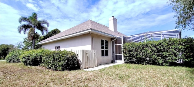 5595 Schefflera, Grant, FL 32949 - view of side of property with stucco siding, a lawn, a chimney, glass enclosure, and roof with shingles