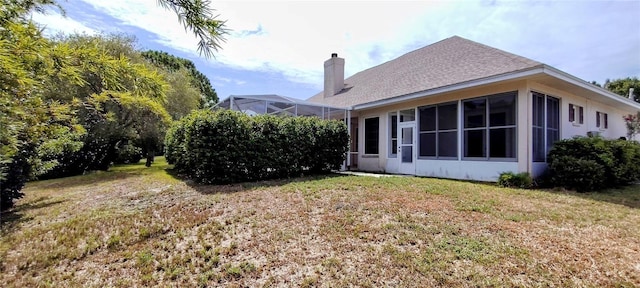 5595 Schefflera, Grant, FL 32949 - back of house with a chimney, a yard, a sunroom, and a shingled roof