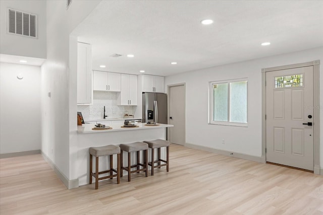 1030 Huntington Ct, Longwood, FL 32750 - kitchen with stainless steel fridge with ice dispenser, a peninsula, light wood-style floors, a breakfast bar, and recessed lighting