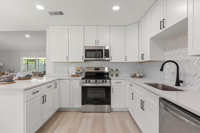 1030 Huntington Ct, Longwood, FL 32750 - kitchen with stainless steel appliances, light countertops, a peninsula, white cabinets, and recessed lighting