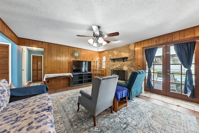 1515 Colonist Ct, Orlando, FL 32818 - living area featuring wood walls, ceiling fan, a textured ceiling, french doors, and a stone fireplace