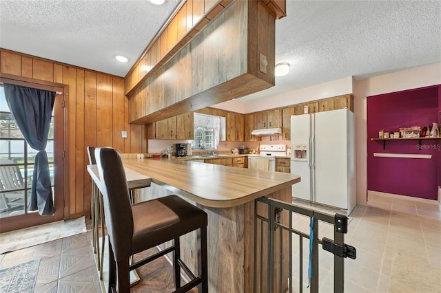 1515 Colonist Ct, Orlando, FL 32818 - kitchen featuring white appliances, a textured ceiling, healthy amount of natural light, brown cabinetry, and a peninsula