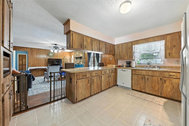 1515 Colonist Ct, Orlando, FL 32818 - kitchen featuring dishwasher, wood walls, brown cabinetry, a peninsula, and a textured ceiling