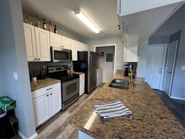 2550 Alafaya Trl Unit 9303, Orlando, FL 32826 - kitchen featuring appliances with stainless steel finishes, wood finished floors, a textured ceiling, white cabinetry, and dark stone counters