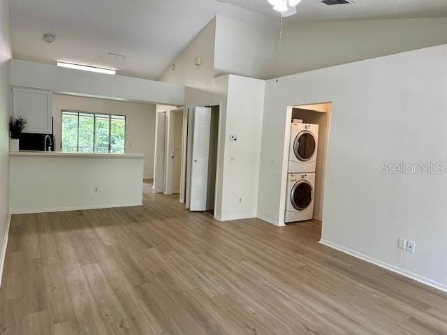 125 Reserve Cir Unit 205, Oviedo, FL 32765 - unfurnished living room with stacked washer / dryer, light wood finished floors, high vaulted ceiling, and a ceiling fan