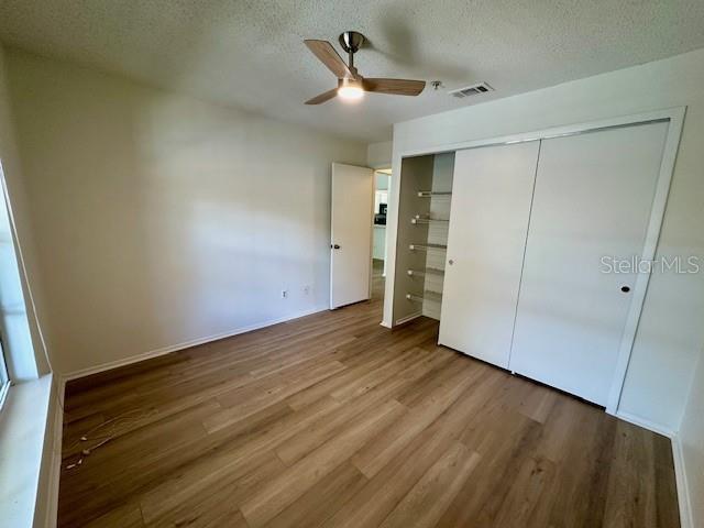 125 Reserve Cir Unit 205, Oviedo, FL 32765 - unfurnished bedroom with wood finished floors, a closet, a textured ceiling, and ceiling fan
