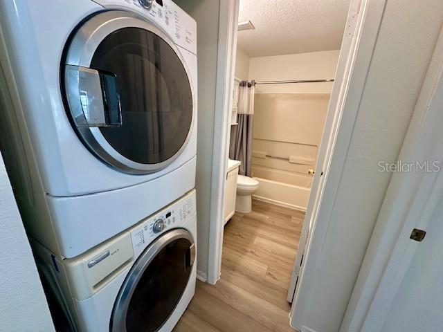 125 Reserve Cir Unit 205, Oviedo, FL 32765 - washroom with estacked washer and dryer, light wood finished floors, and a textured ceiling