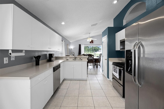 527 Durango Loop St, Davenport, FL 33897 - kitchen featuring appliances with stainless steel finishes, a textured ceiling, a peninsula, lofted ceiling, and white cabinetry