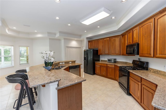 1908 S Farm Rd, Deland, FL 32720 - kitchen featuring black appliances, a raised ceiling, a center island with sink, ornamental molding, and light stone countertops