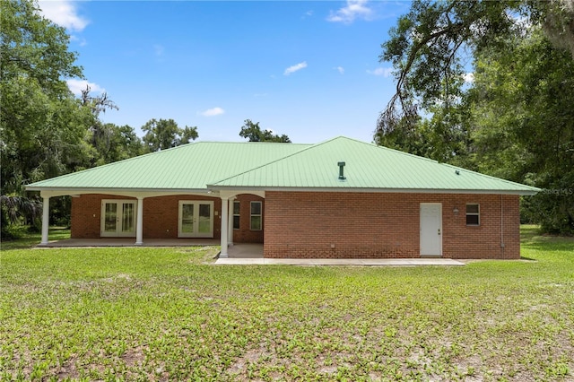 1908 S Farm Rd, Deland, FL 32720 - back of house featuring french doors, a lawn, a patio, brick siding, and a metal roof