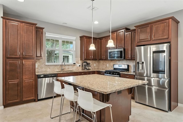 1110 Pine Falls Ln, Ocoee, FL 34761 - kitchen with appliances with stainless steel finishes, light stone countertops, a center island, decorative light fixtures, and tasteful backsplash