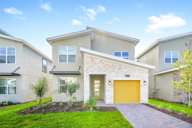 9175 Sommerset Hills Dr, Davenport, FL 33896 - contemporary home with stone siding, decorative driveway, stucco siding, and an attached garage