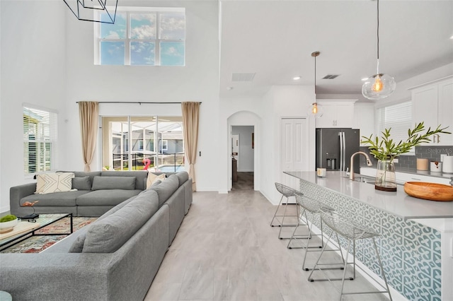 9175 Sommerset Hills Dr, Davenport, FL 33896 - living area featuring arched walkways, light wood finished floors, a high ceiling, and recessed lighting