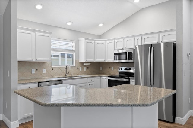 449 Timmonsville Way, The Villages, FL 32162 - kitchen with stainless steel appliances, vaulted ceiling, wood finished floors, white cabinetry, and decorative backsplash