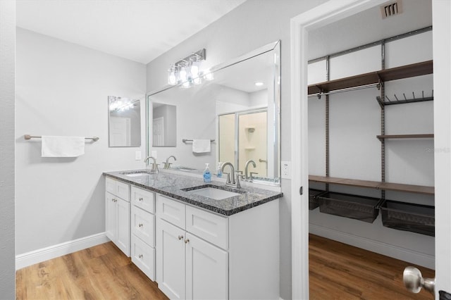 449 Timmonsville Way, The Villages, FL 32162 - bathroom with wood finished floors, double vanity, and a stall shower