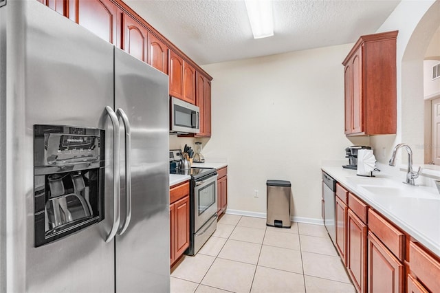 4114 Breakview Dr Unit 110, Orlando, FL 32819 - kitchen featuring stainless steel appliances, a textured ceiling, arched walkways, light countertops, and light tile patterned floors