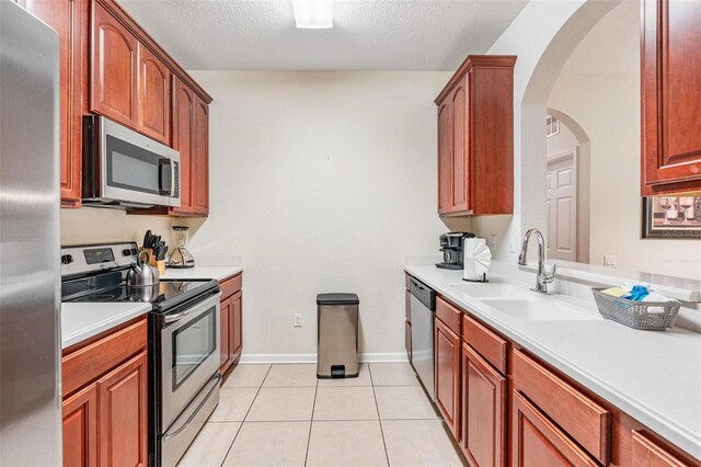 4114 Breakview Dr Unit 110, Orlando, FL 32819 - kitchen with stainless steel appliances, light countertops, a textured ceiling, light tile patterned flooring, and arched walkways