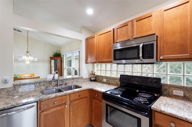 162 Canary Island Cir, Davenport, FL 33837 - kitchen featuring appliances with stainless steel finishes, vaulted ceiling, tasteful backsplash, light stone counters, and hanging light fixtures