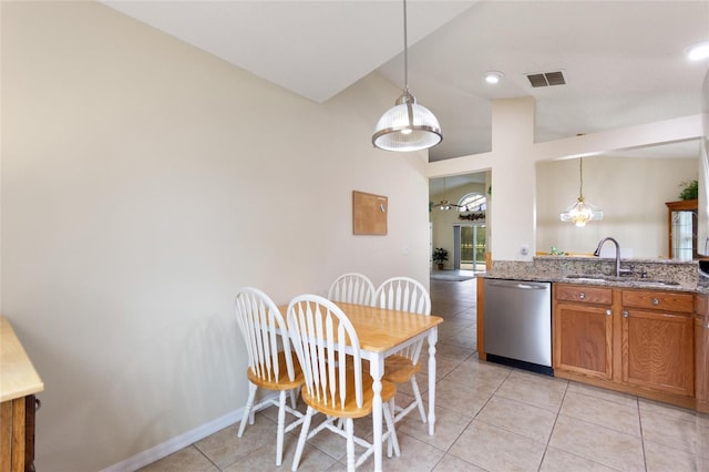 162 Canary Island Cir, Davenport, FL 33837 - kitchen featuring stainless steel dishwasher, lofted ceiling, brown cabinets, light tile patterned floors, and decorative light fixtures